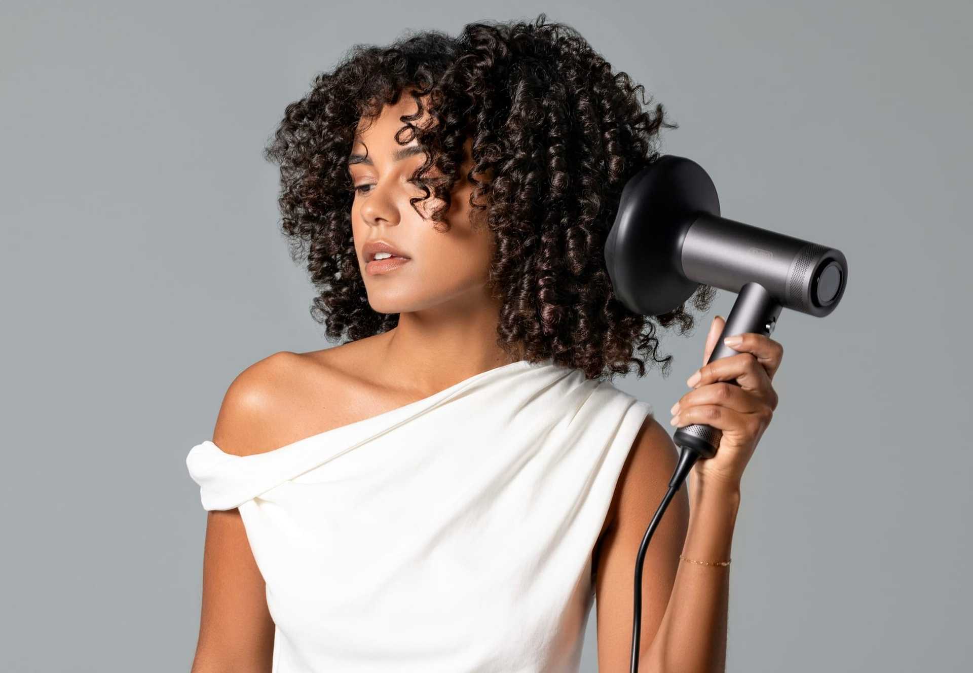 Woman with curly hair using a diffuser hairdryer.